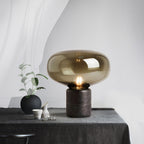Amber glass mushroom table lamp on a dark linen-draped table with a small black vase