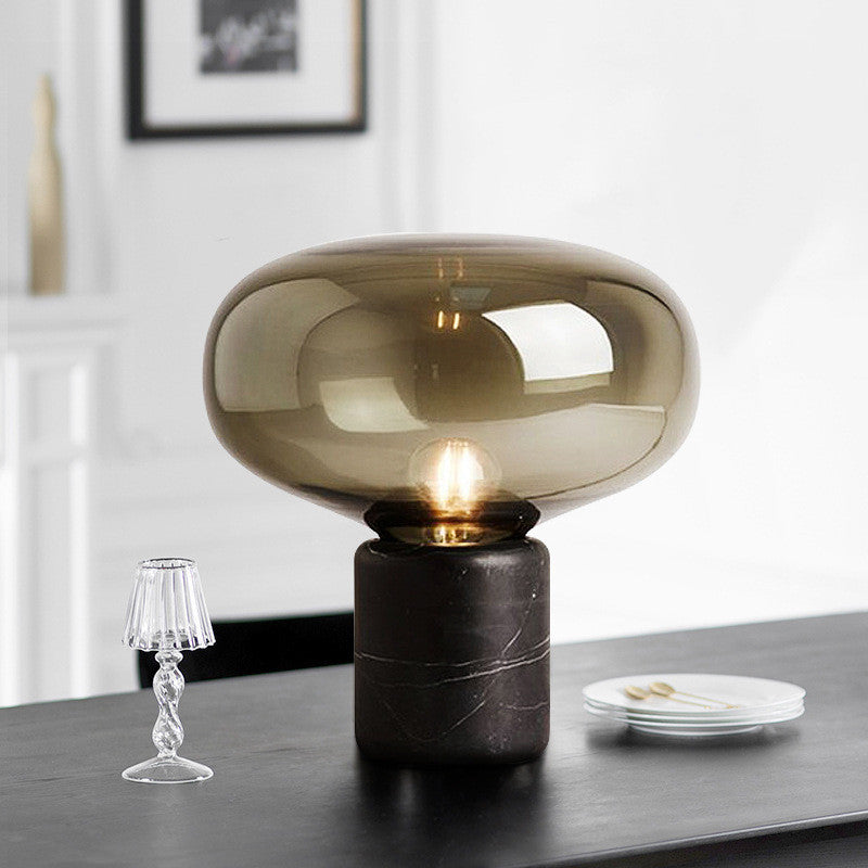 Amber glass mushroom table lamp lit on a black table — close view of the glass dome