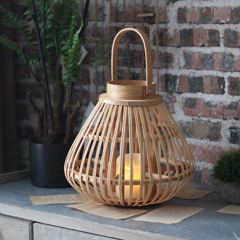 Bamboo lantern candle holder glowing on a zinc-topped console against a whitewashed brick wall