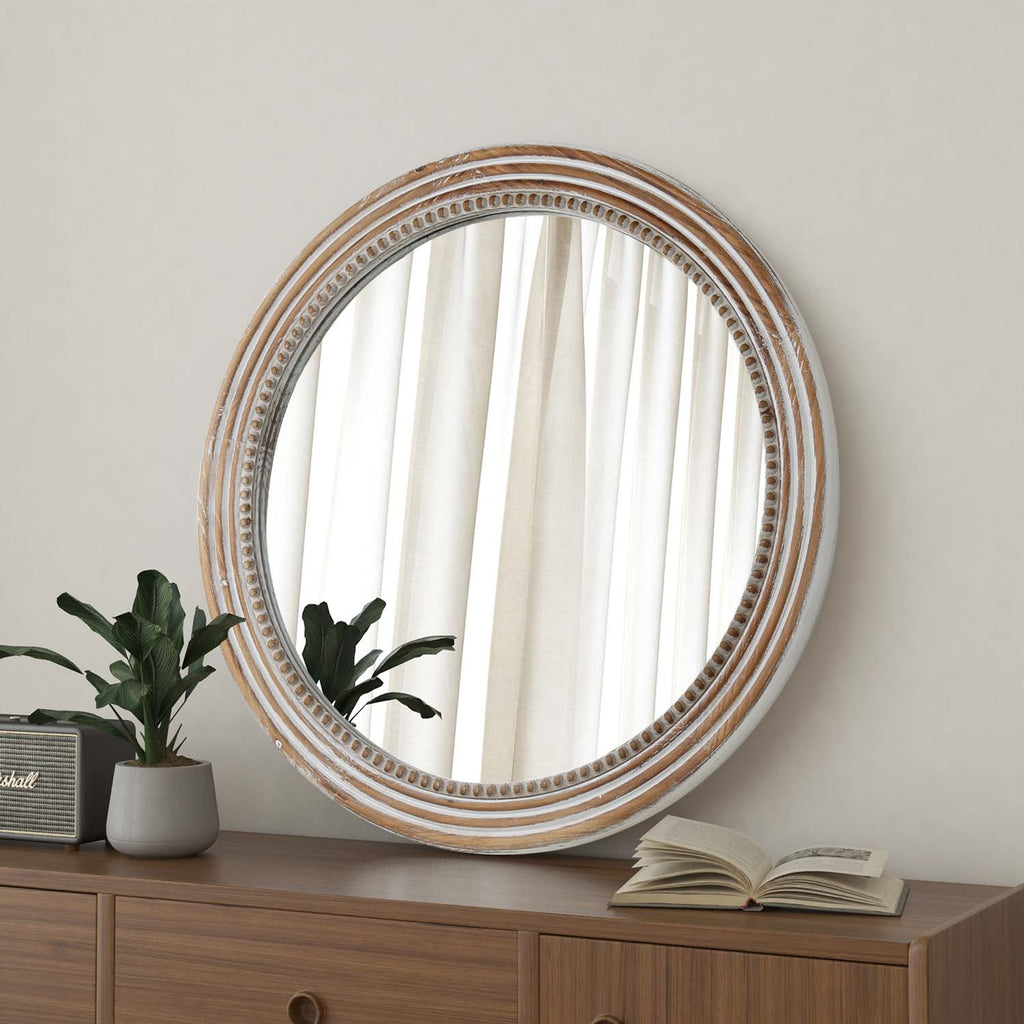 Whitewashed round mirror with bead detail angled above a walnut dresser