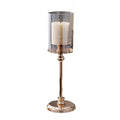 Champagne gold pedestal hurricane candle holder with a clear sleeve and pillar candle, on a plain white background
