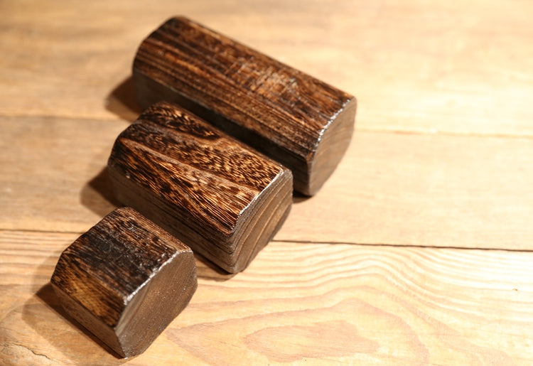 Charred paulownia tealight holders laid on their sides — detail of the raised wood grain