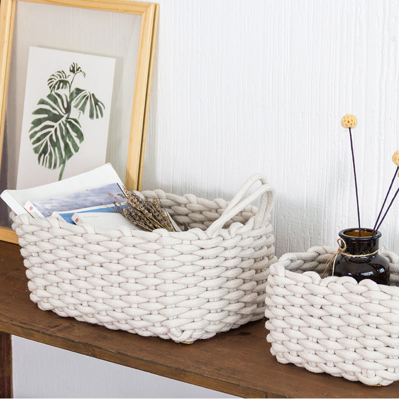 Chunky ivory cotton rope storage baskets, large and small, on a wooden console against a white wall