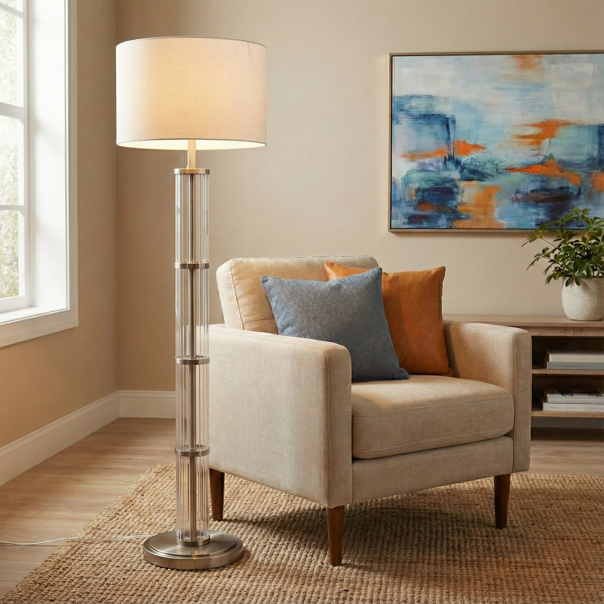Glass column floor lamp lit beside a linen armchair in a sunny living room