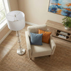 Glass column floor lamp seen from above beside a cream armchair on a jute rug