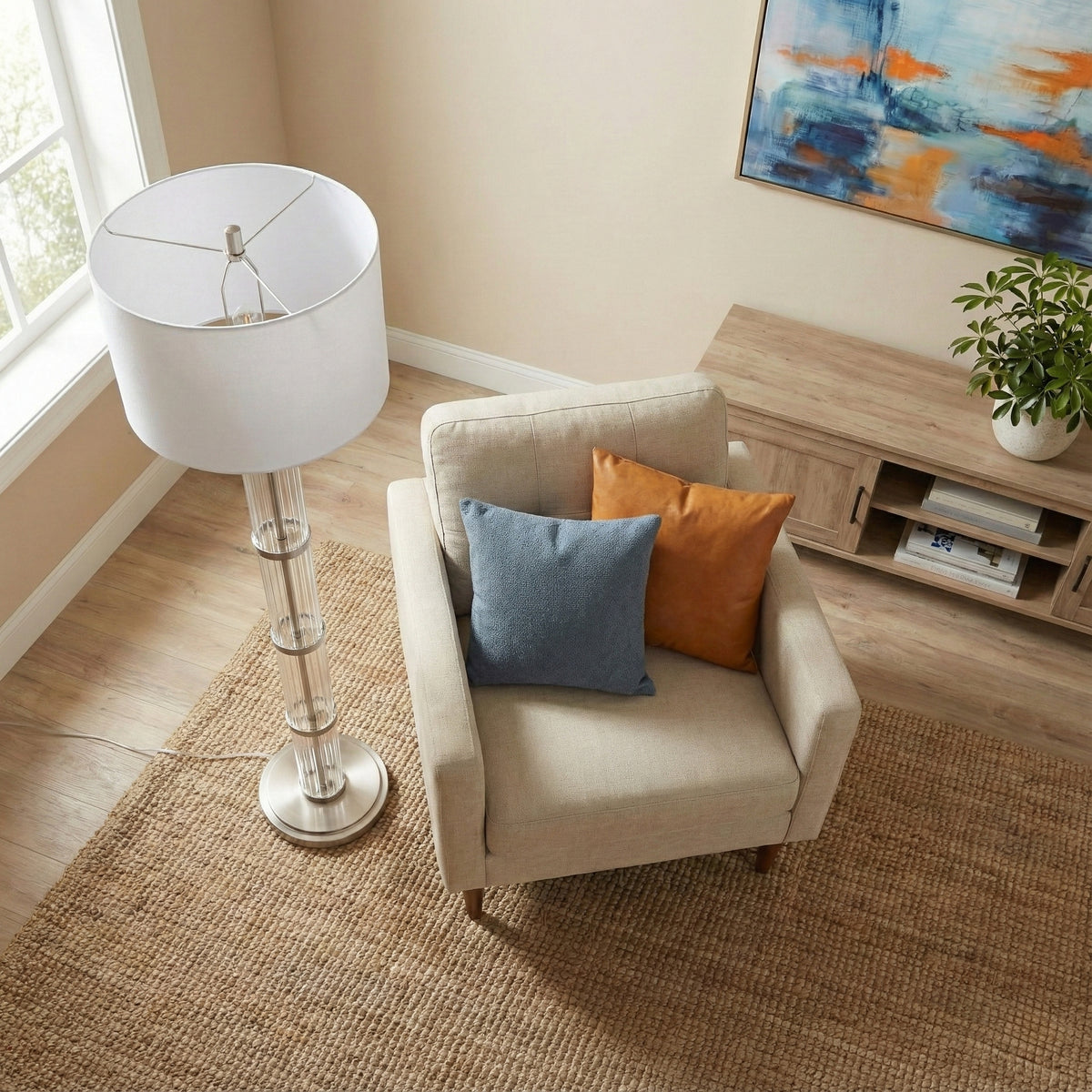 Glass column floor lamp seen from above beside a cream armchair on a jute rug