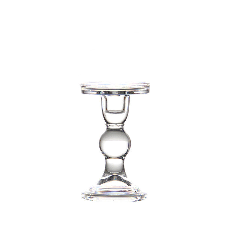 Tall clear glass pillar candle holder with a ball stem on a plain white background