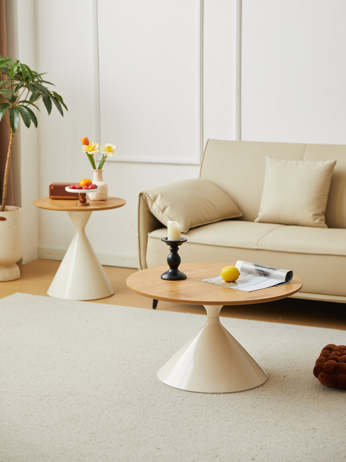 Round oak-grain coffee table with a candlestick, the taller side table behind it by the sofa