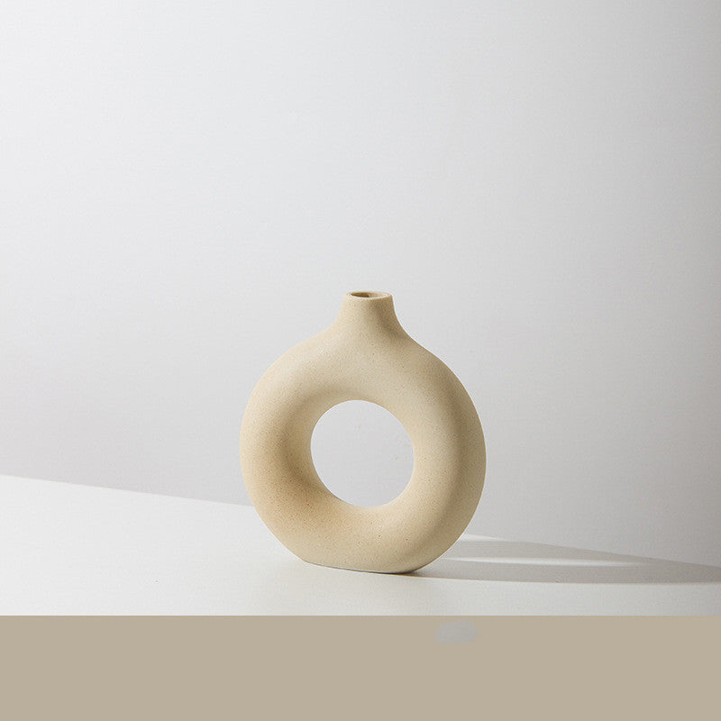 Donut ring porcelain bud vase in sand, small size, on a white tabletop against a pale wall