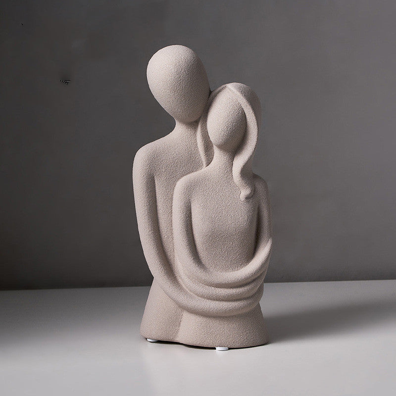 Abstract embracing couple sculpture in grey speckled stone, on a plain grey backdrop