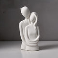 Abstract embracing couple sculpture in white speckled stone, on a plain grey backdrop
