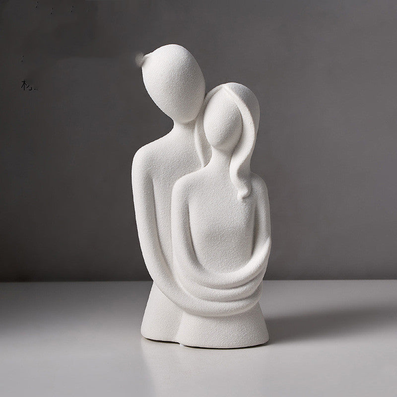 Abstract embracing couple sculpture in white speckled stone, on a plain grey backdrop