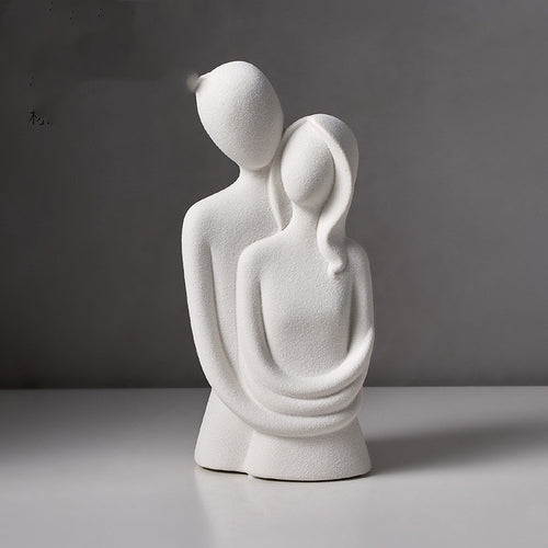Abstract embracing couple sculpture in white speckled stone, on a plain grey backdrop