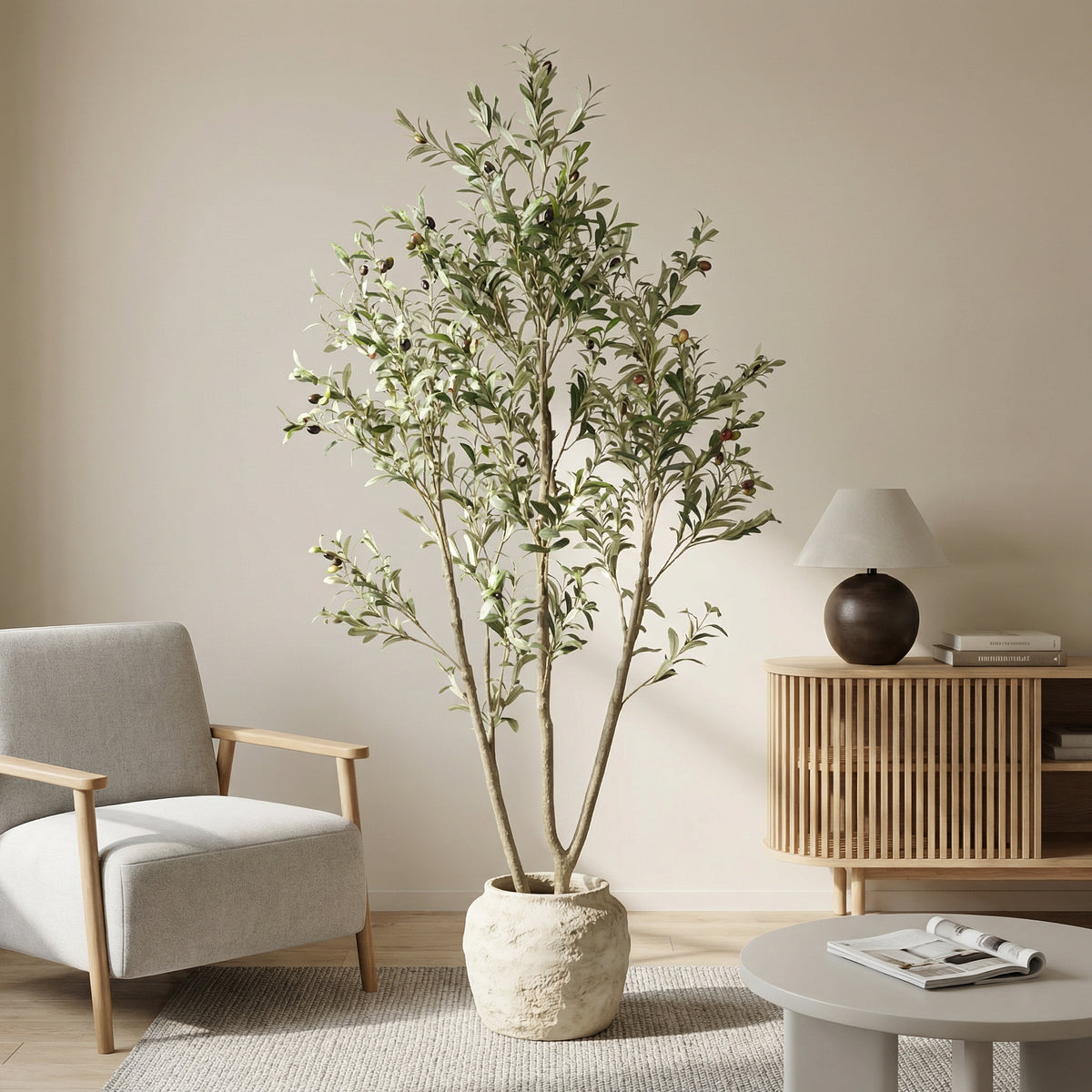 Faux olive tree in a stone planter, not included, beside a linen armchair and table lamp