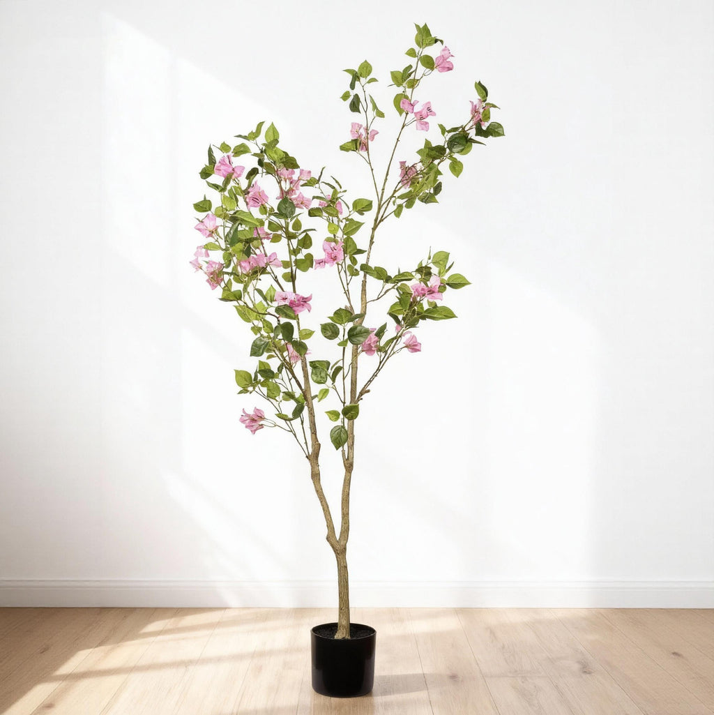5 ft faux pink bougainvillea tree in its black pot against a white wall on a wood floor