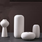 Fine-ribbed white ceramic vases, set of four with the spool vase, on a dark grey studio backdrop