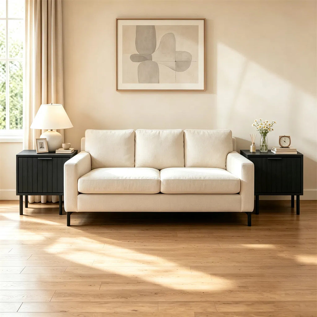 Two fluted black nightstands either side of a cream sofa