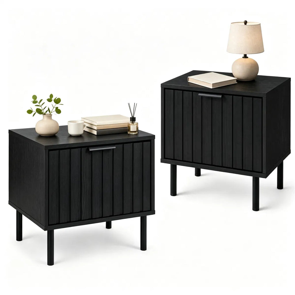 Two fluted black nightstands styled with a lamp, books and a vase on a white background