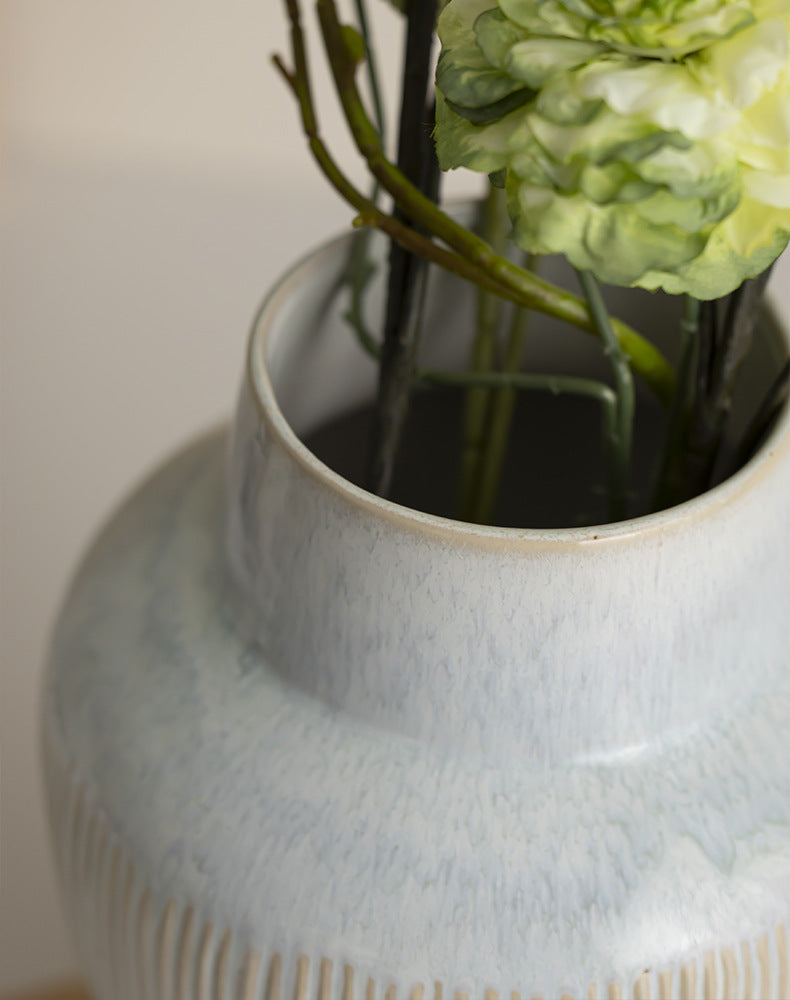 Fluted ceramic vase — close view of the glazed rim with green stems inside
