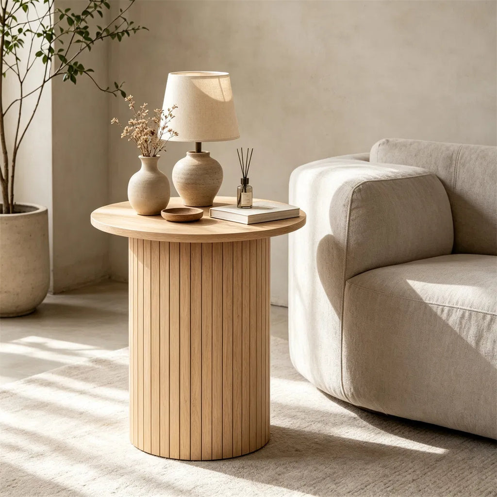 Fluted drum side table beside a cream sofa with a table lamp and vases on top