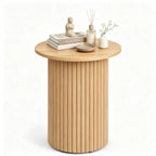 Fluted pedestal side table styled with books and a diffuser on a plain white background