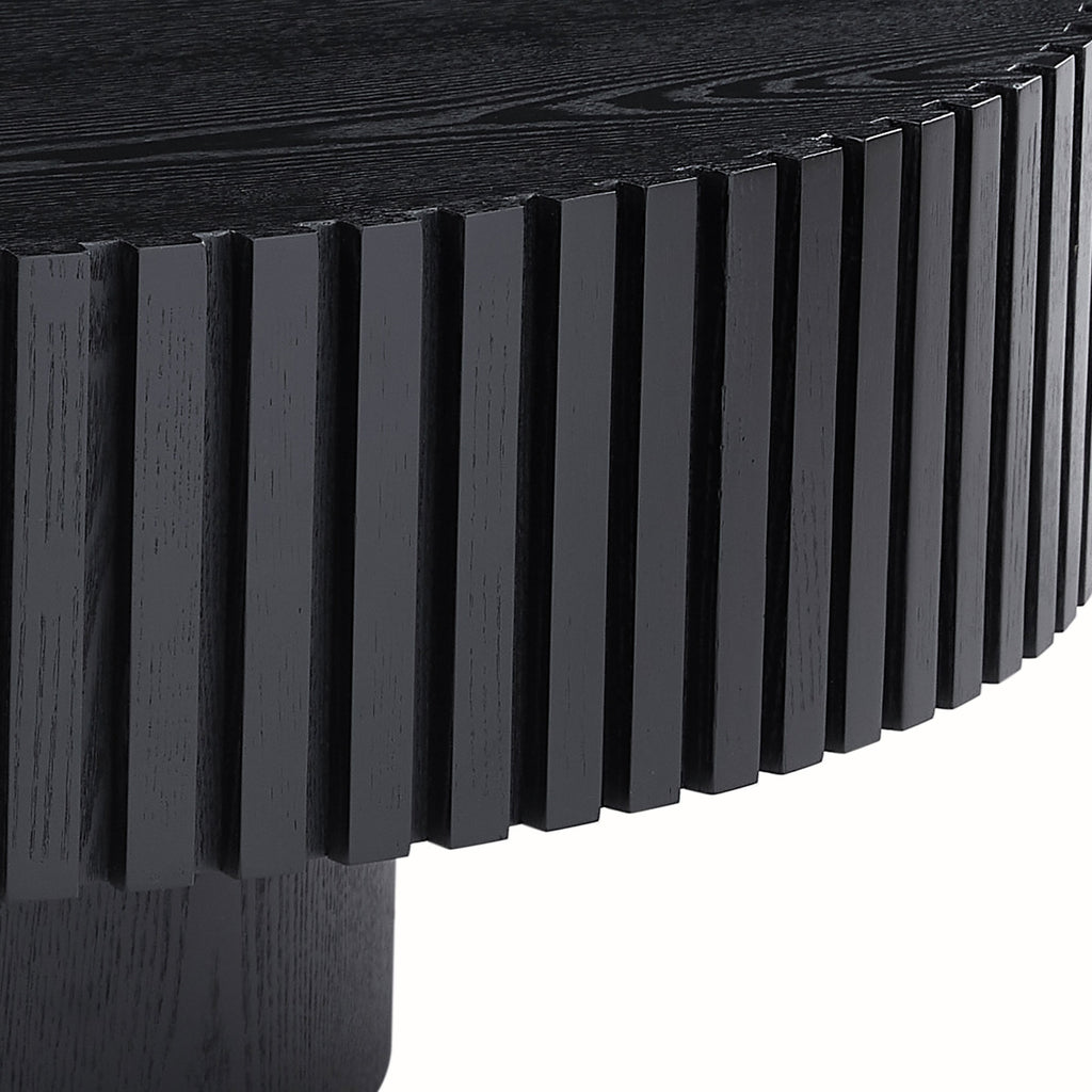 Fluted drum coffee table — detail of the vertical ribs over the recessed black pedestal