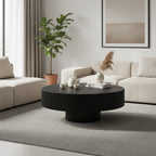 Black drum coffee table with fluted edge in front of a cream sofa, styled with a vase
