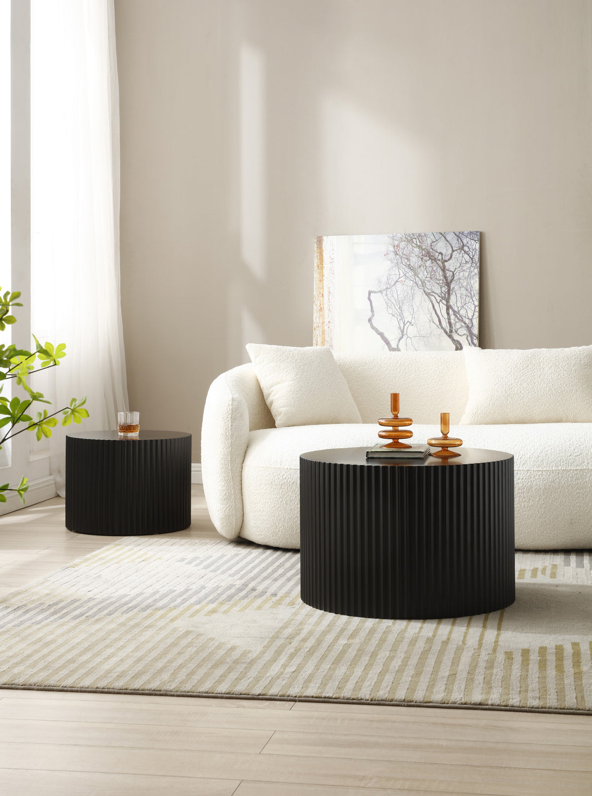 Black fluted drum tables set apart, the small one beside the sofa as a side table