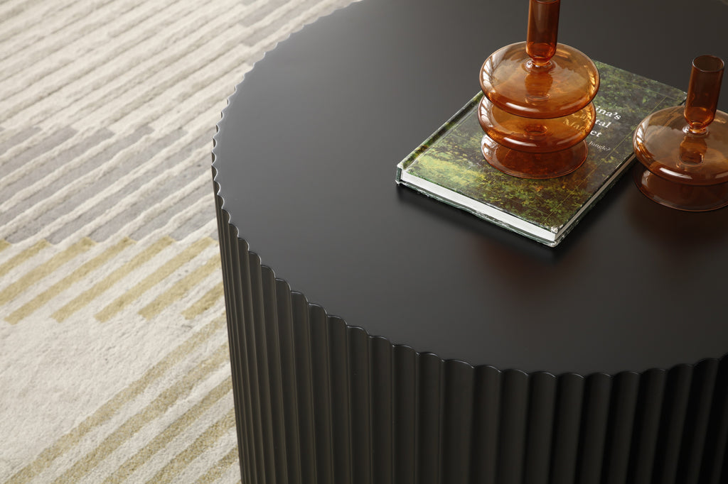 Matte black fluted drum table — close view of the round top and ribbed side on a striped rug