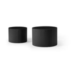 Small and large fluted black drum tables side by side, on a plain white background