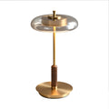 Glass disc table lamp with walnut grip and brass-tone stem on a plain white background