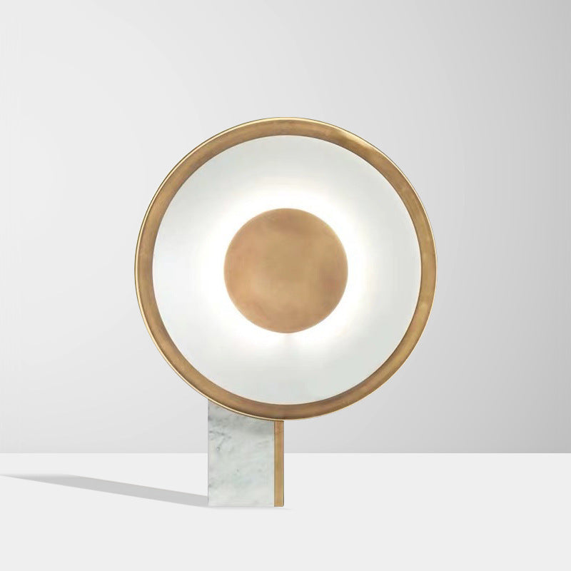 Halo ring lamp lit on a pale table with a soft shadow