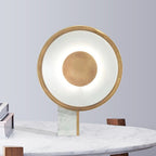 Gold-tone ring table lamp on a white marble block, set on a marble table