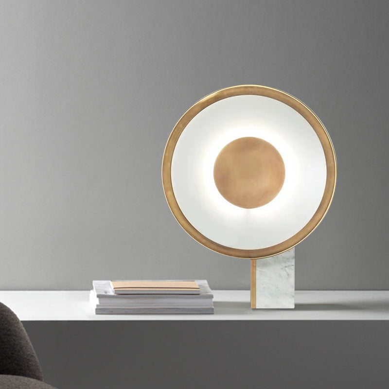 Halo ring lamp glowing on a white shelf against a grey wall