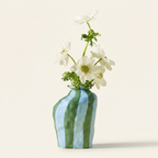 Striped ceramic flower vase in glossy blue and green on a warm cream background