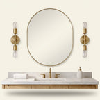 Modern 2-Light Wall Sconce with Clear Glass Shades, Gold Finish, for Bathroom Vanity Over Mirror on a warm cream background