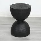 Burnt mango wood hourglass side table on a pale grey wood floor against a white wall