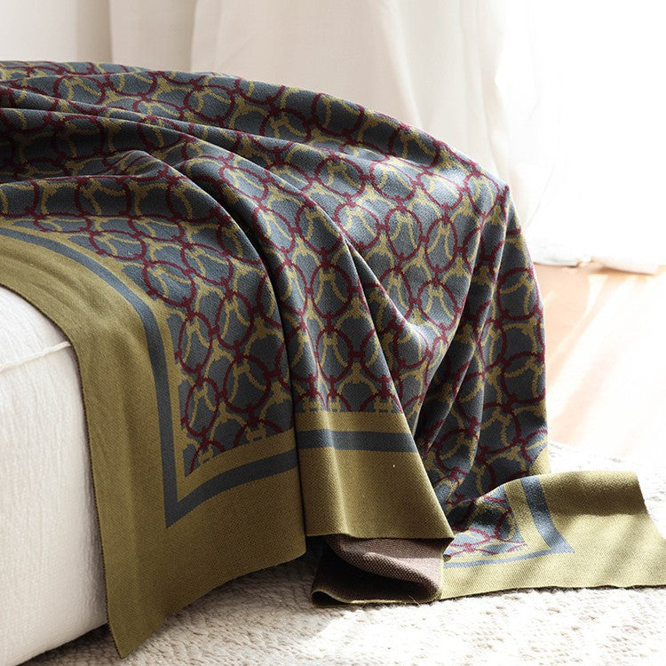 Olive ring-pattern knit throw draped over a white sofa onto a cream rug