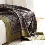 Olive ring-pattern knit throw draped over a white sofa onto a cream rug