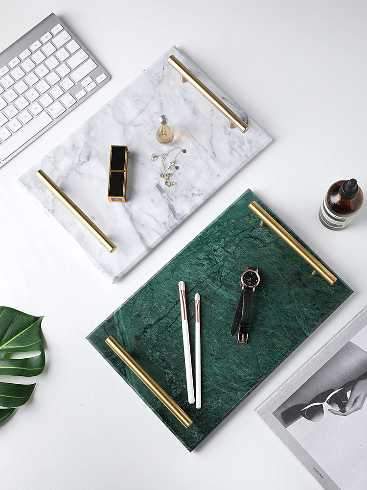 White and green marble trays with gold-tone handles on a desk beside a keyboard