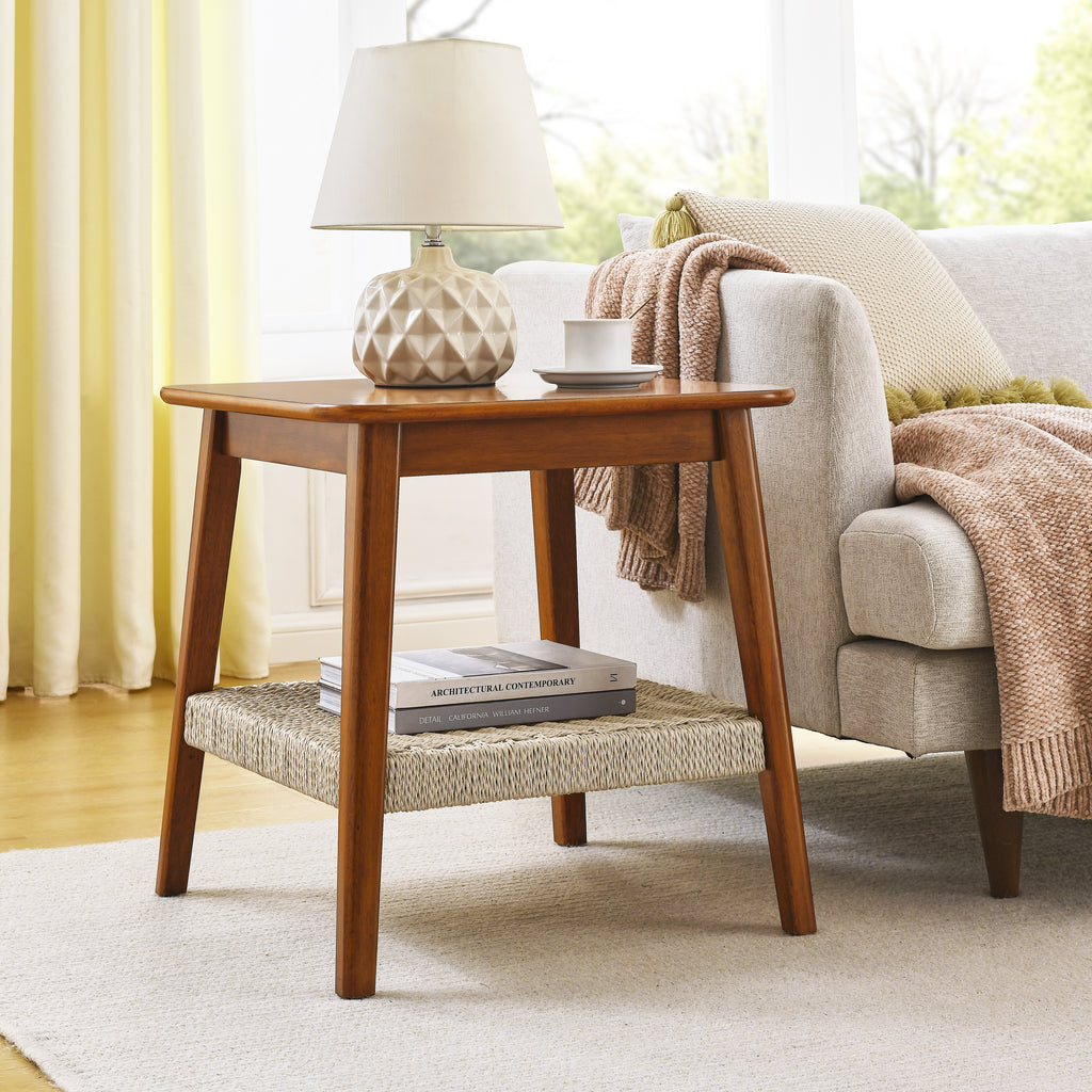 Walnut-tone side table with woven shelf beside a cream sofa under a ceramic table lamp