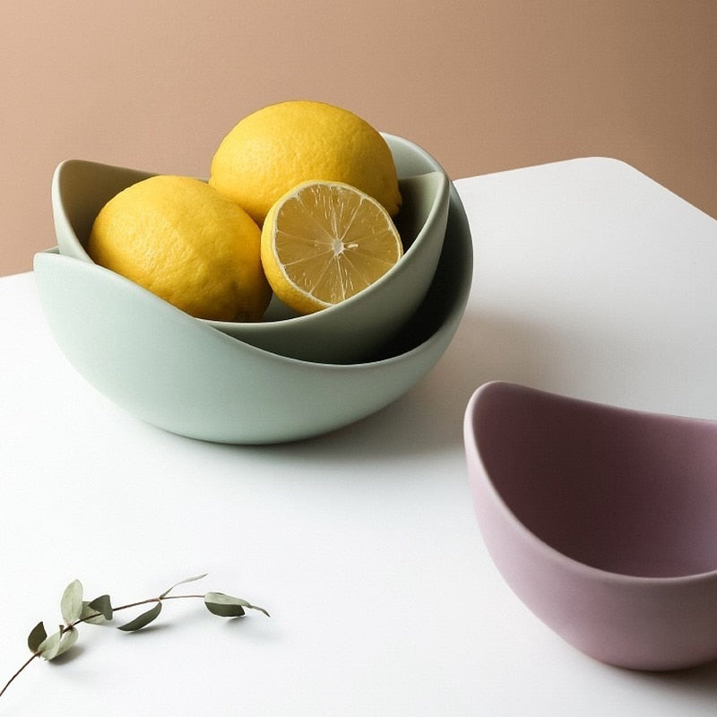 Sage ceramic lotus bowls holding lemons, with a lilac bowl beside them on a white table
