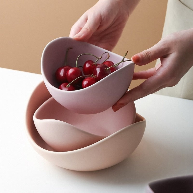 Lilac ceramic lotus bowls being lifted apart, the top bowl holding cherries