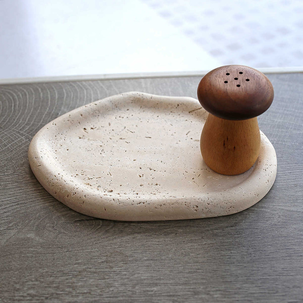 Beige travertine catchall tray with a wooden mushroom shaker — detail of the rolled rim and pores