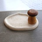 Beige travertine catchall tray with a wooden mushroom shaker — detail of the rolled rim and pores