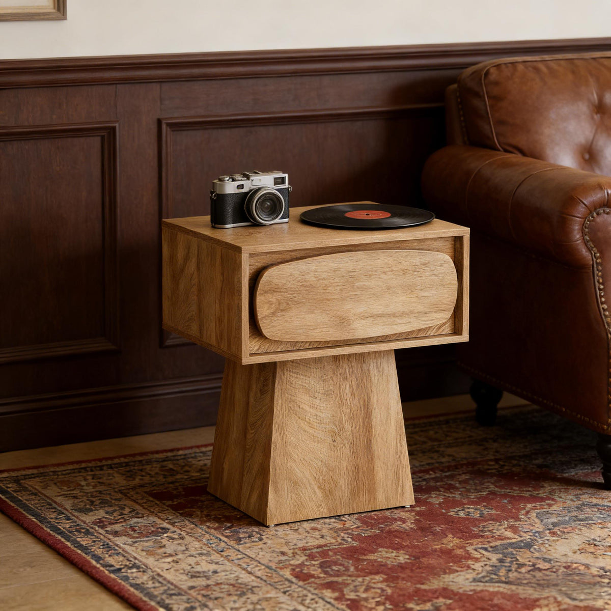 Oak-look pedestal side table beside a leather sofa with a camera and a vinyl record