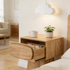Oak-look pedestal side table by a bed with its rounded drawer pulled open