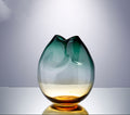 Pinched ombre glass vase in teal and amber on a pale grey studio background