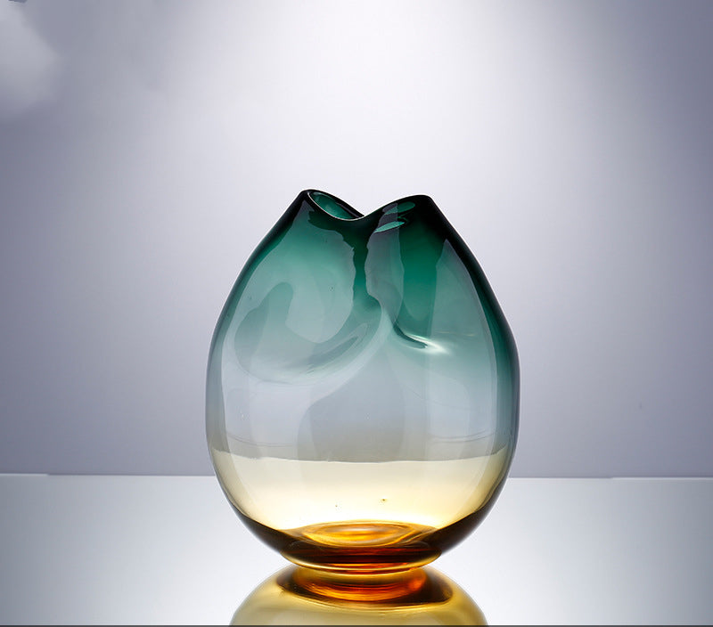 Pinched ombre glass vase in teal and amber on a pale grey studio background