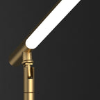 Brass desk lamp — detail of the pivot knuckle under the lit light bar